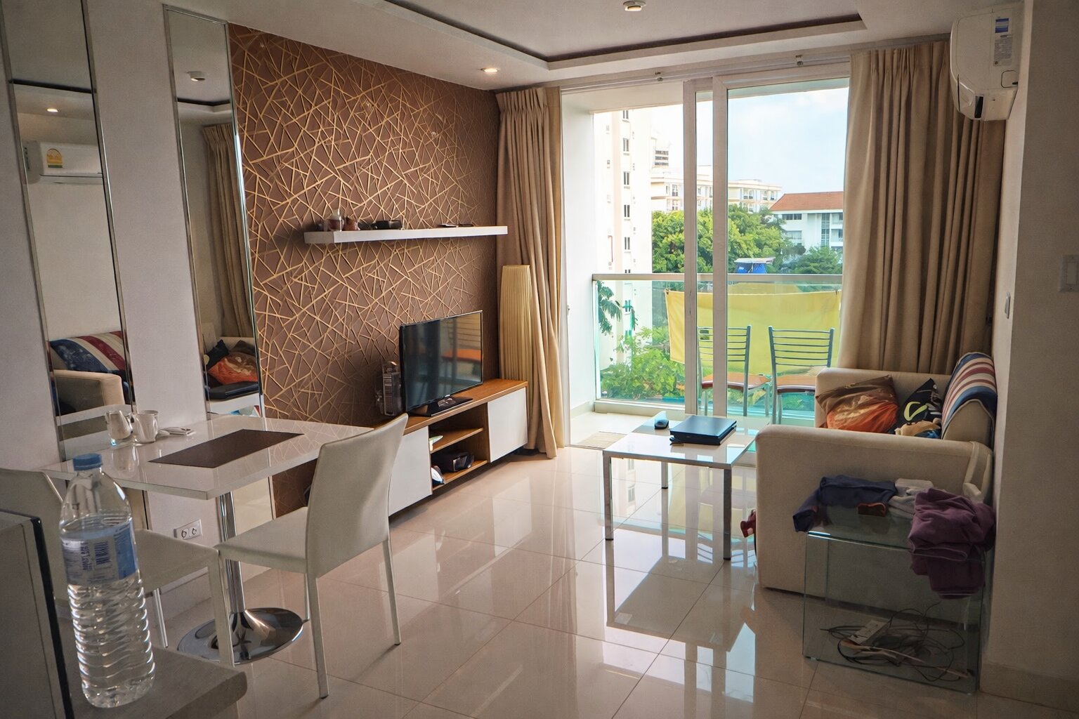 Типичная студия в кондо — телевизор, кондиционер, балкон с видом на район