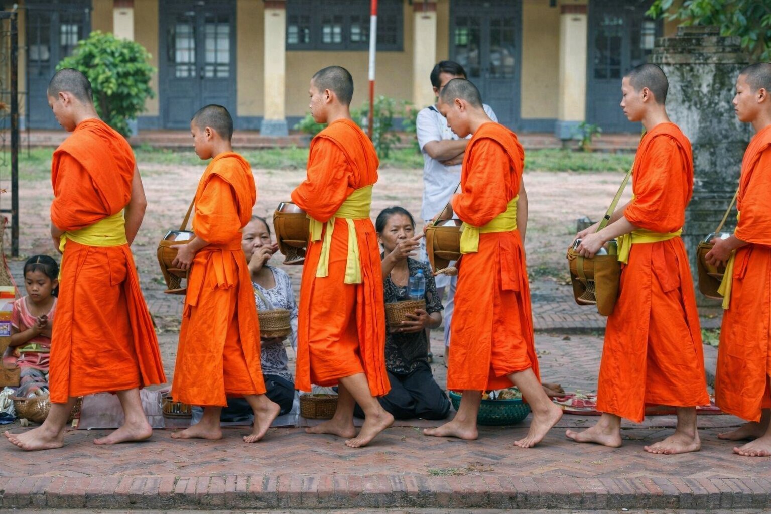 Буддийские монахи в оранжевых одеждах идут за утренним подаянием — этикет и культура Таиланда