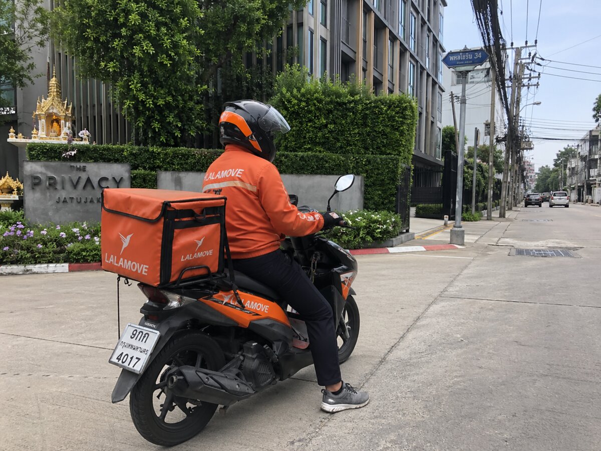 Курьер доставки на мотобайке у кондо в Таиланде