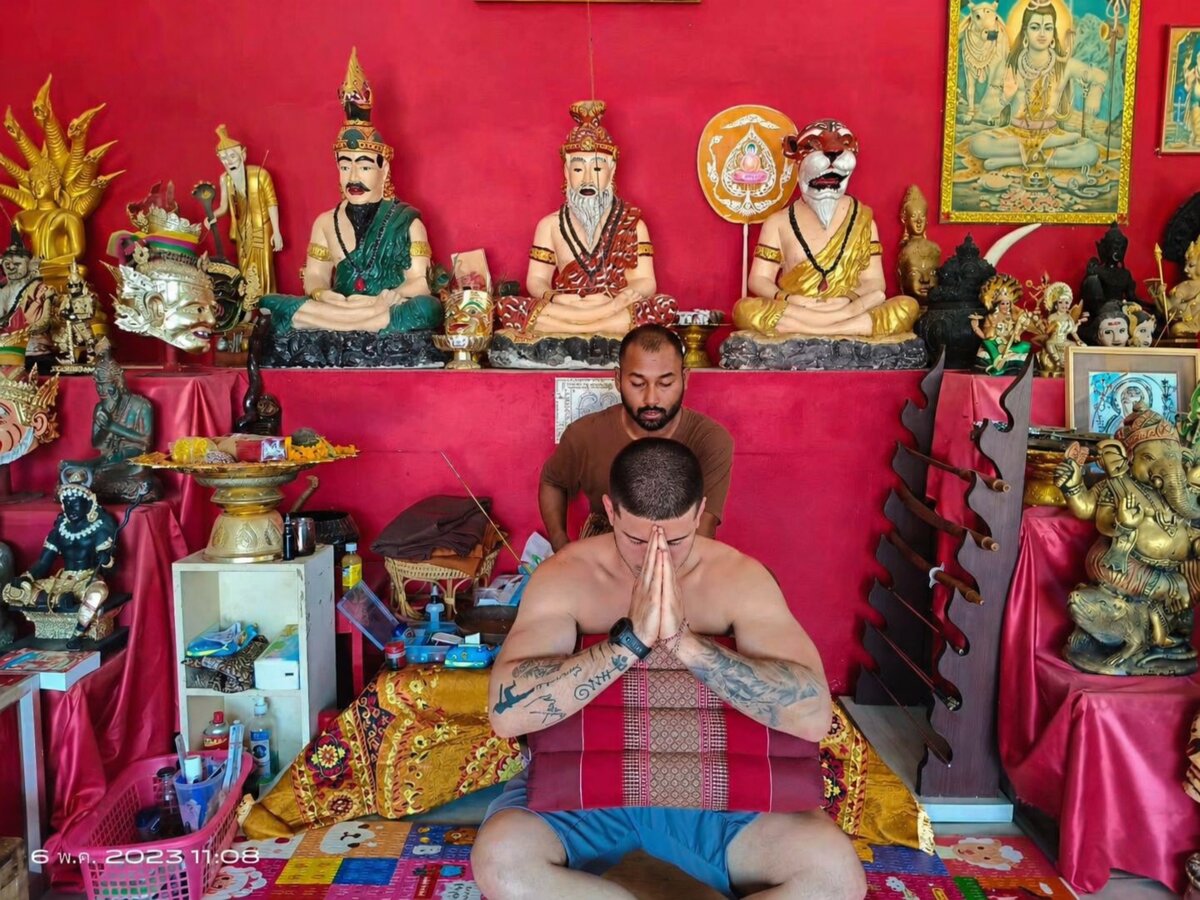 Церемония нанесения Сак Янт — аджан и турист в традиционной позе вай