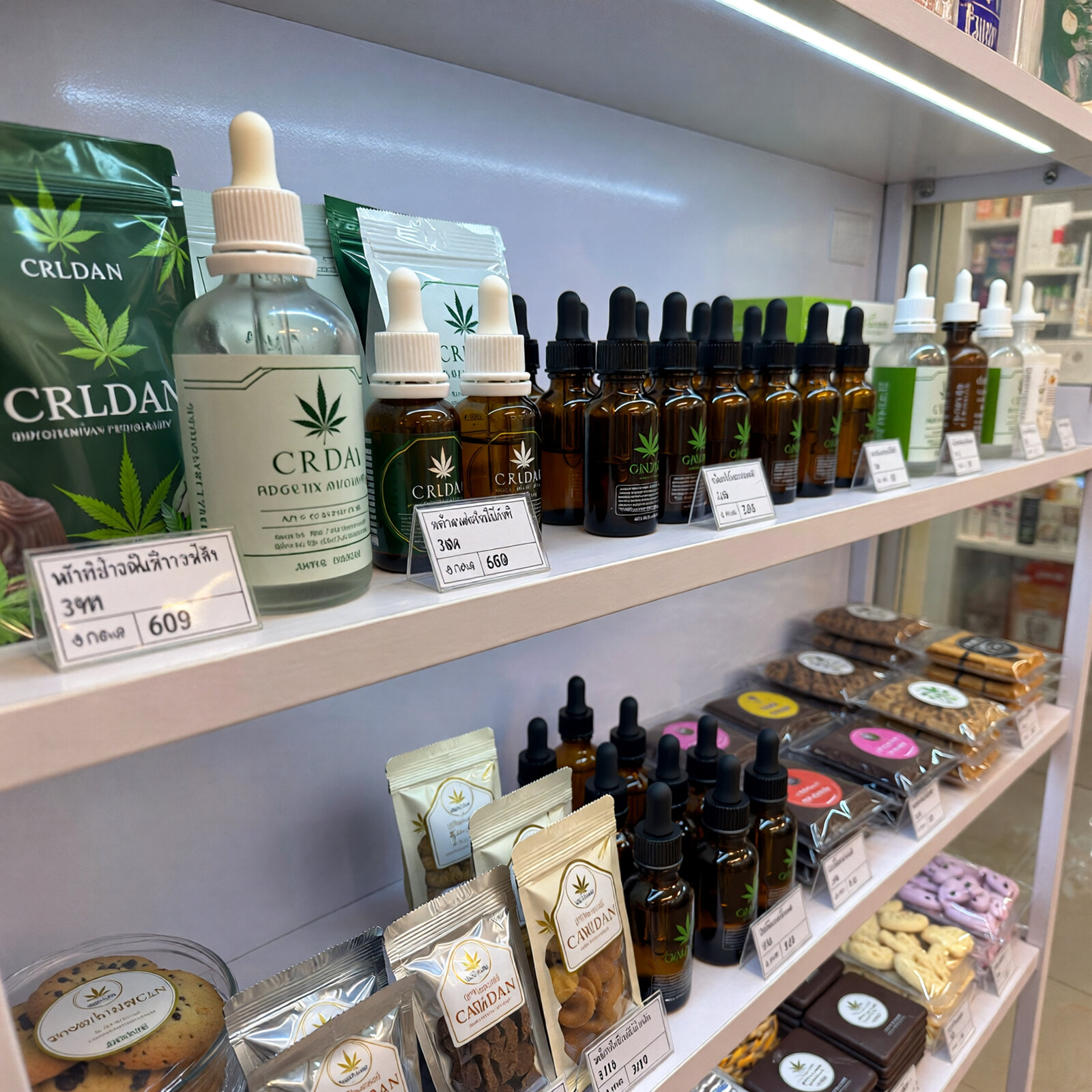 CBD-масла и каннабис-продукты на полке тайского диспансера с ценниками в батах